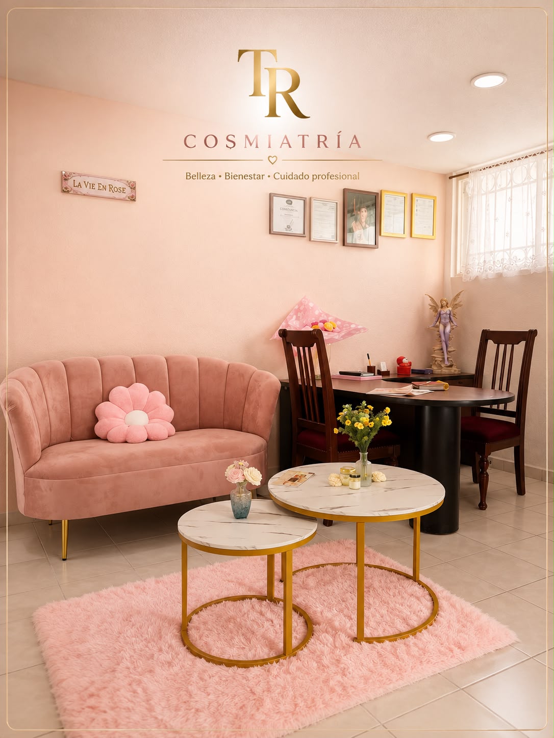 Sala de espera de TR Cosmiatría con sillón rosa y mesas de mármol